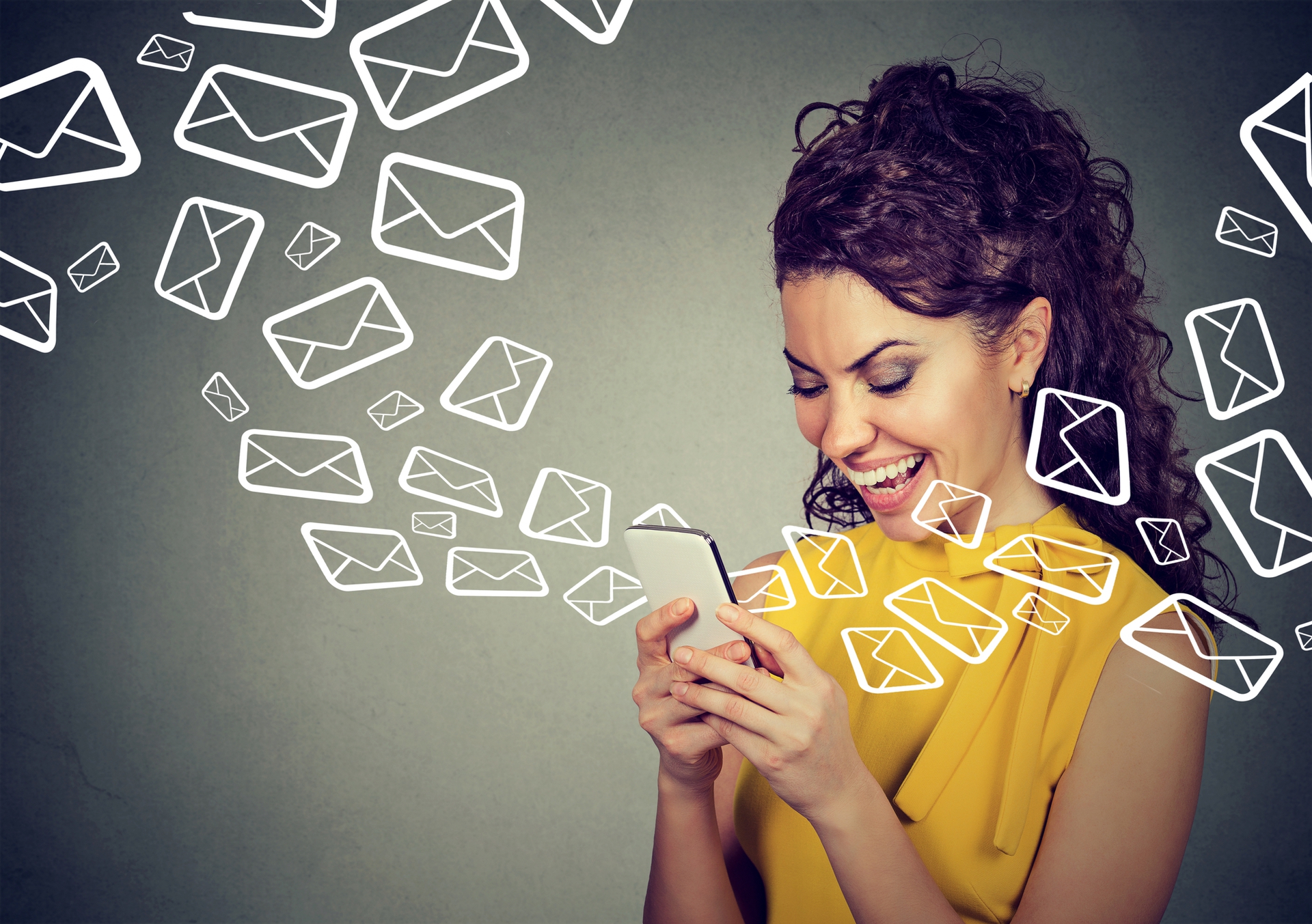 happy woman looking at her phone with swirling email icons around her head
